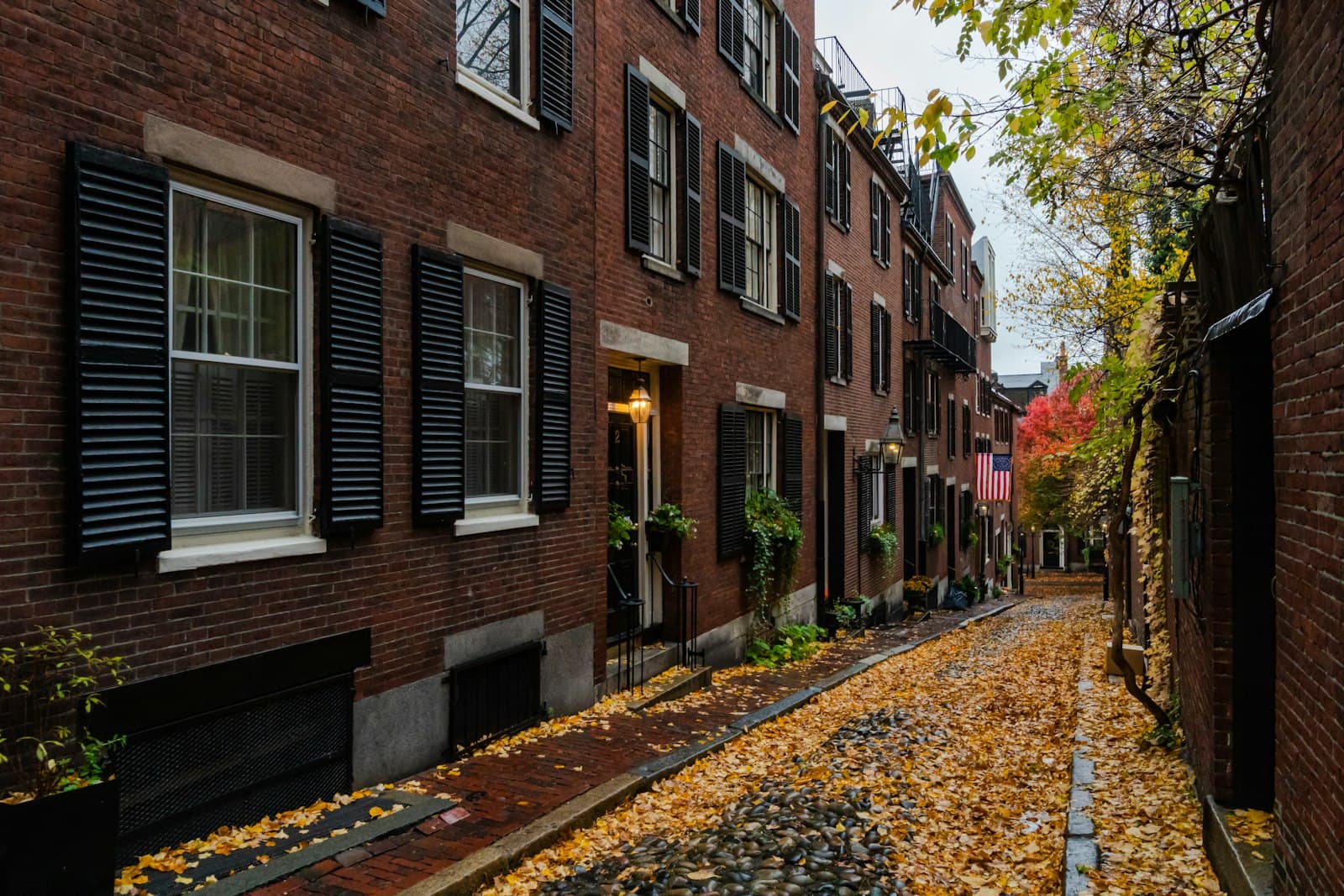 Acorn Street in Beacon Hill, Boston, lined with brick row houses and autumn leaves