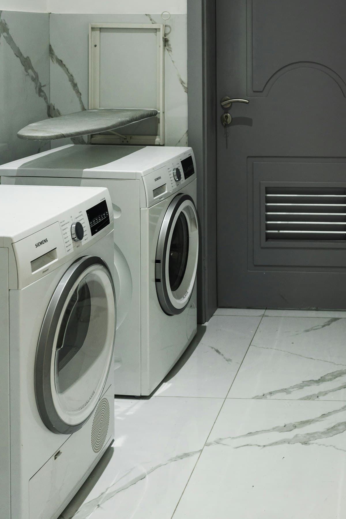 Front-load washer and dryer side by side in a tiled laundry room