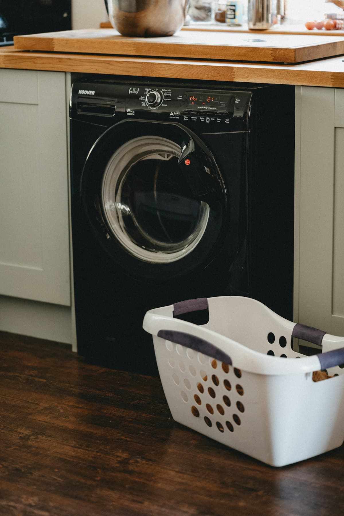 Black front-load washing machine under a wooden counter